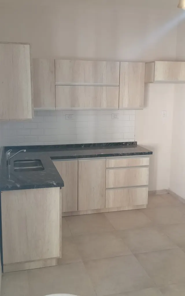 Cocina en L con alacenas en melamina clara y azulejos blancos