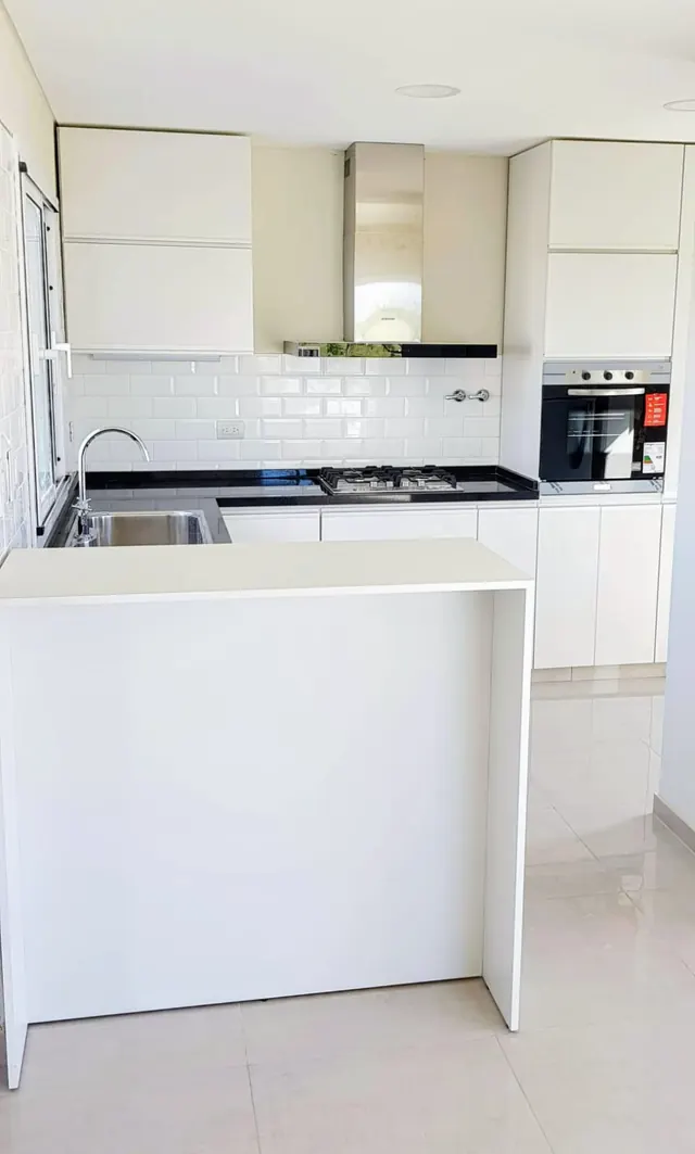 Cocina blanca con barra, horno y revestimiento símil ladrillo blanco