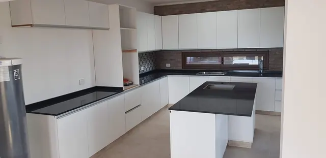 Cocina en L blanca con isla y mesada negra