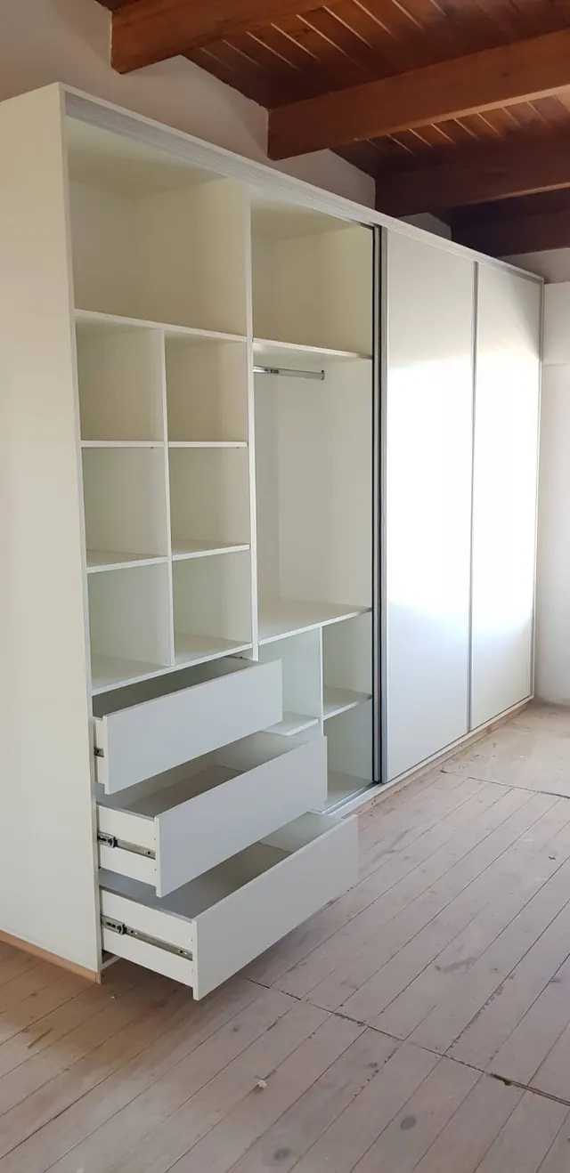 Interior de placard blanco con estantes, percheros y cajones