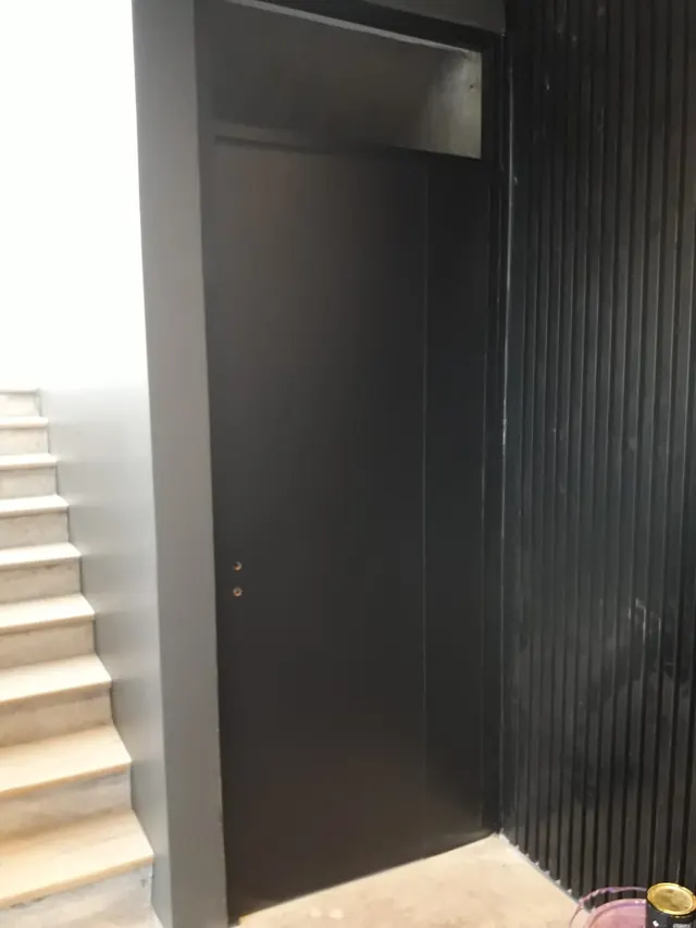 Puerta negra junto a revestimiento varillado